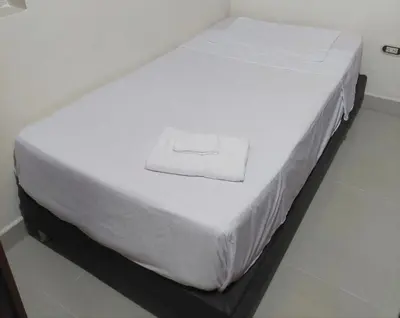 a white bed with a white towel on it at Cápsula Urbana Central #4 in Medellín