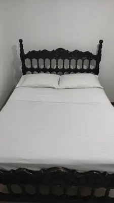 a bed with a black frame and white sheets at Habitación, con baño privado #7 in Medellín