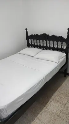 a bed with white sheets and a wooden headboard at Habitación, con baño privado #7 in Medellín