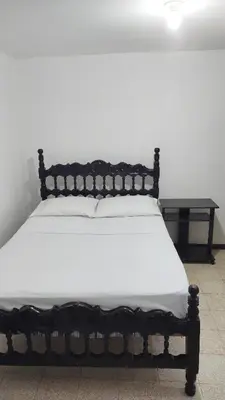 a bed with a black frame and white sheets at Habitación, con baño privado #7 in Medellín