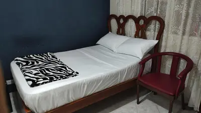 a small bed with a red chair and a pillow and a bedskirts at Hab. Cama doble y baño privado #3 in Medellín