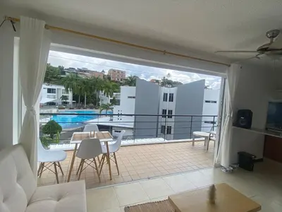 a living room with a balcony with a table and chairs at Apartasol Santa Fe de Antioquia - Ciudadela Santa Fe in Santa Fe de Antioquia