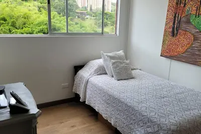 a small bedroom with a bed and two windows at Estándar Suite en Sabaneta in Sabaneta
