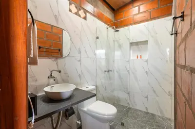 a bathroom with a white toilet and a sink at HOTEL EMBRUJO CAMPESTRE in Jardin