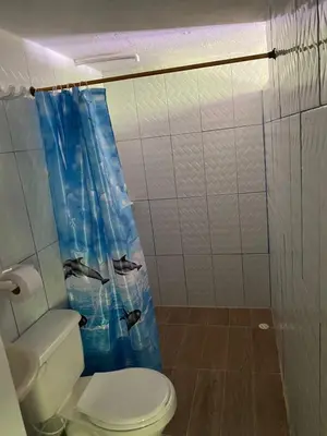 a bathroom with a toilet and a blue shower curtain at Mirador del Magdalena in Doradal