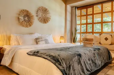 a bedroom with a large white bed and a window at Poblado Muuk Hotel Boutique Campestre in Medellín