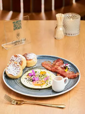 a plate of breakfast food with bacon and donuts on a table at Poblado Muuk Hotel Boutique Campestre in Medellín