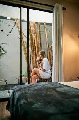a woman sitting in a chair in front of a window at Poblado Muuk Hotel Boutique Campestre in Medellín