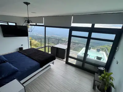 a bedroom with a bed and a tub on a balcony at Cabaña en Sopetran con jacuzzi in Sopetran