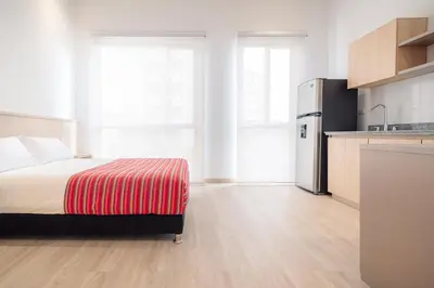 a bedroom with a bed and a kitchen at Hotel Estar in Manizales