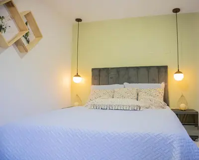 a bedroom with a large white bed with two lights at Apartamento cómodo, agradable y económico in Medellín