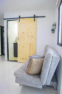 a couch in a living room with a wooden door at Apartamento cómodo, agradable y económico in Medellín