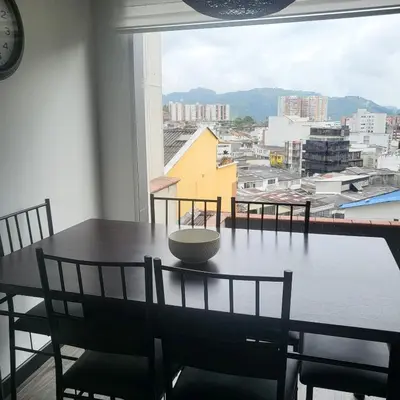 a dining room table with chairs and a large window at LA CASA DEL CABLE -Comodo Apartamento 102- in Manizales