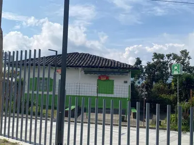 a white building with a green door behind a fence at LA CASA DEL CABLE -Comodo Apartamento 102- in Manizales