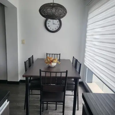 a dining room table with chairs and a clock on the wall at LA CASA DEL CABLE -Comodo Apartamento 102- in Manizales