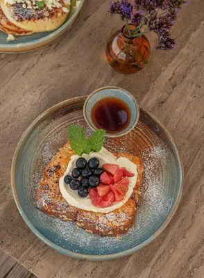 a plate of pancakes with fruit and a cup of syrup at The Brown, Guatape, Autograph Collection in Guatapé