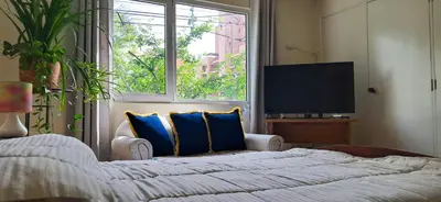 a bedroom with a bed with blue pillows and a television at Habitación Privada en Apartamento, Conquistadores in Medellín