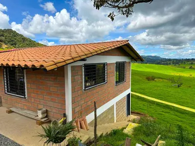 a small brick house with a green field behind it at Casa de Campo en San Pedro in San Pedro