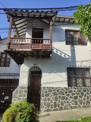 a white house with a porch and a balcony at Hostal prado colonial in Medellín