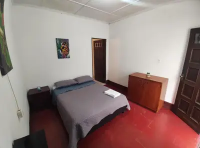 a bedroom with a bed and a dresser and a door at Hostal prado colonial in Medellín