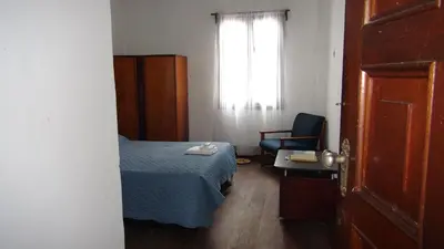 a bedroom with a bed and a chair and a window at Hostal prado colonial in Medellín