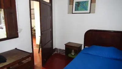 a bedroom with a blue bed and a wooden door at Hostal prado colonial in Medellín