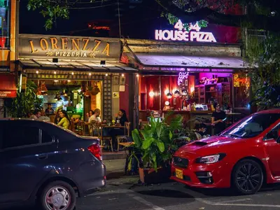 two cars parked in front of a restaurant at night at Elemont Hotel in Medellín
