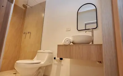 a bathroom with a toilet and a sink and a mirror at Elemont Hotel in Medellín