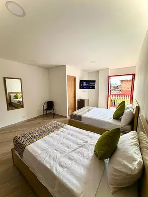 a bedroom with two beds and a tv on the wall at ALTO VERDE HOTEL in Guatapé
