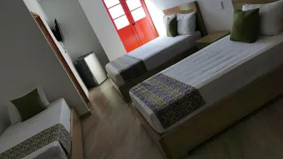 a small room with two beds and a window at ALTO VERDE HOTEL in Guatapé