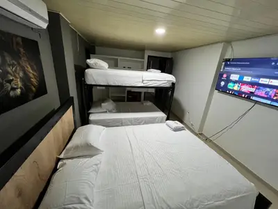 a small room with three bunk beds and a tv at Hotel Entre Parques in La Dorada
