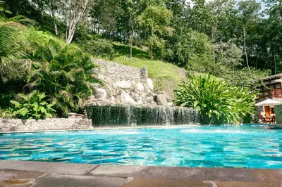 a swimming pool with a waterfall in a yard at Bio Rio Hotel in San Jerónimo