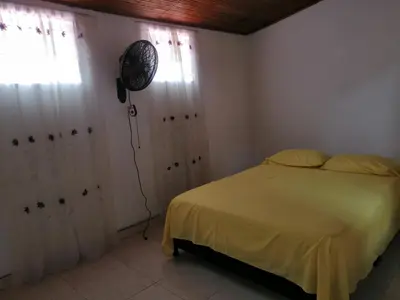 a bedroom with a bed and a fan on the wall at casa de relajación lowcost in La Dorada