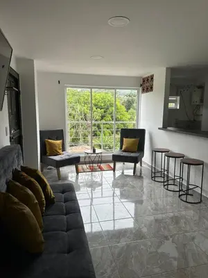 a living room with a couch and chairs and a large window at Sencillo apartamento en Guatape in Guatapé
