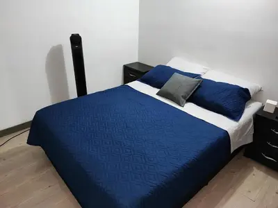 a bed with a blue blanket and pillows on it at Apartamento con piscina, frente a CC Mayorca in Sabaneta