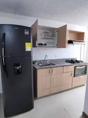 a kitchen with a black refrigerator and a sink at Apartamento con piscina, frente a CC Mayorca in Sabaneta