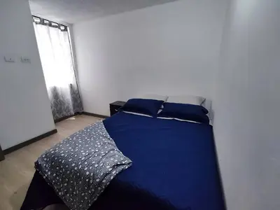 a bedroom with a bed with blue sheets and a window at Apartamento con piscina, frente a CC Mayorca in Sabaneta