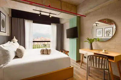 a bedroom with a bed and a desk and a window at Urbit Social Lofts in Medellín
