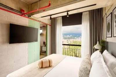 a bedroom with a bed and a large window at Urbit Social Lofts in Medellín