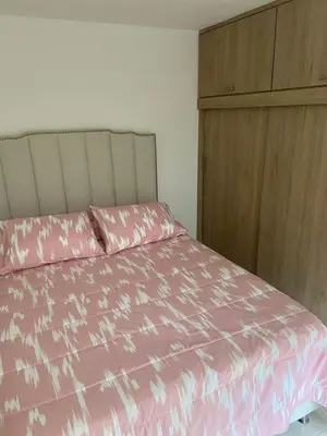 a bedroom with a pink bed and a wooden cabinet at Cómodo apto para disfrutar su estadia in Medellín
