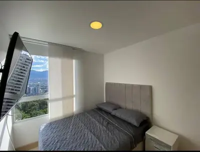 a bedroom with a bed and a large window at apto poblado a 8 min de provenza con free parking in Medellín