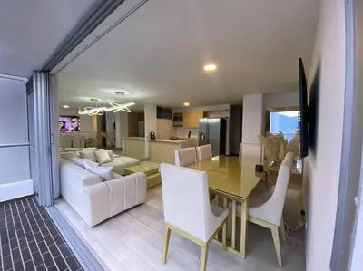 a dining room and living room with a table and chairs at apto poblado a 8 min de provenza con free parking in Medellín