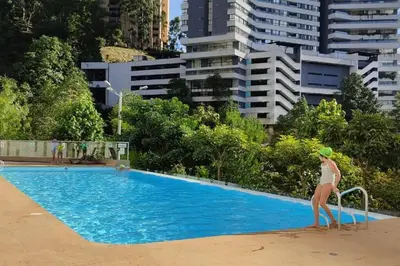 a woman in a bikini standing next to a swimming pool at apto poblado a 8 min de provenza con free parking in Medellín