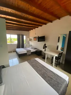 a bedroom with two beds and a desk and a tv at 33 Hotel Bulerias in Medellín