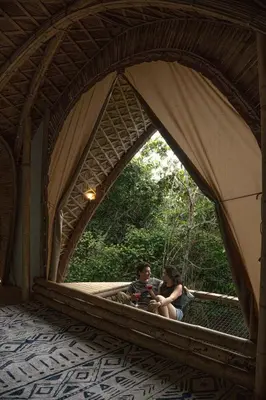 two people sitting on a bridge in a tent at Taibará Refugio Natural in San Carlos