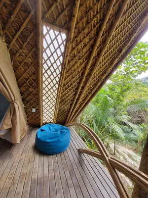 a room in a tree house with a blue bed on a wooden deck at Taibará Refugio Natural in San Carlos