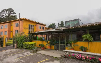 a restaurant with a yellow building with flowers in a parking lot at Hotel Valjala in Manizales