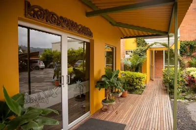 a yellow building with a wooden porch with plants at Hotel Valjala in Manizales