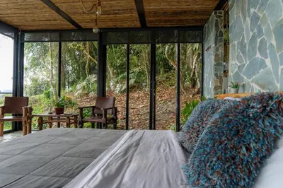 a bedroom with a large bed with glass windows at GLAMPING ENTRE MONTES Y CAFETALES in Santuario