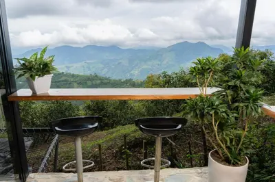 a bar with two stools and a view of mountains at GLAMPING ENTRE MONTES Y CAFETALES in Santuario